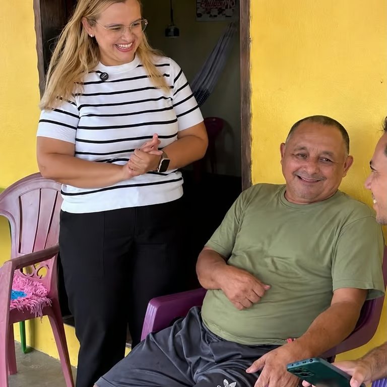 Paulinha Braga em visita domiciliar, conversando com morador sentado na varanda de casa em Itapipoca