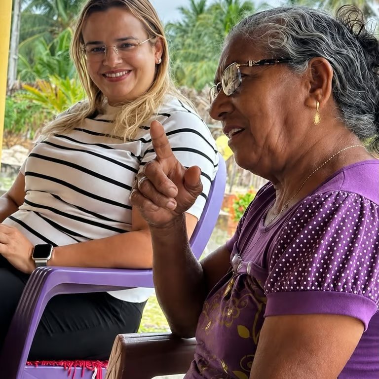Paulinha Braga ouvindo atentamente uma senhora da comunidade durante conversa ao ar livre