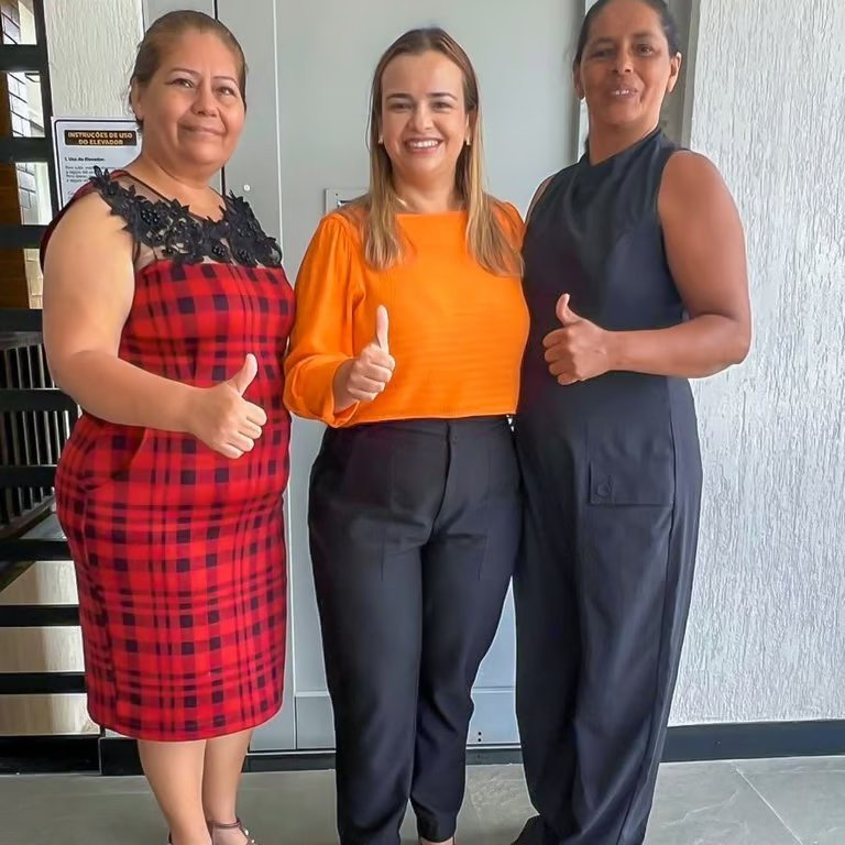 Paulinha Braga entre duas apoiadoras que fazem sinal de positivo durante encontro